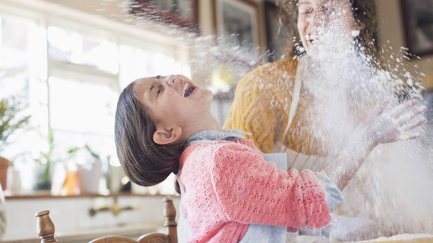 Mother and daughter playing with flour in the kitchen